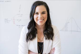 Headshot of Katelyn Jetelina, Ph.D., MPH, a white woman with long dark hair in a white blazer and black shirt smiling at the camera with her arms crossed.