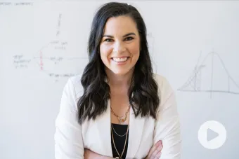 Headshot of Katelyn Jetelina, Ph.D. — a white woman with long, brown hair, standing in front of a white board wearing a white blazer and black top smiling at the camera.