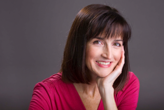 Headshot of Anita Vangelisti, a white woman with short brown hair wearing a bring pink shirt and smiling at the camera