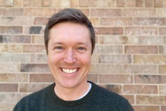 Headshot of Andrew (Drew) Coolidge, a white man with short brown hair with blue eyes, clean shaven, wearing a dark green sweater, and smiling at the camera.
