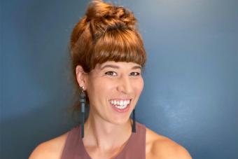 Headshot of Remington Johnson, a woman with reddish-brown hair in a bun wearing a dusty pink tank top and smiling at the camera