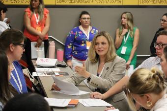 A group of women sitting around a desk talking during the 2024 Health Communication Leadership Institute