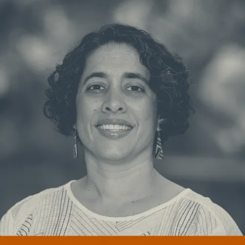 Headshot of Shirene Garcia, a Latina woman with short, dark, curly hair wearing a white top and smiling at the camera.